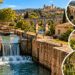 Canal histórico no sul da França com eclusas de pedra, embarcação turística, aqueduto em arcos e vegetação ao longo das margens.