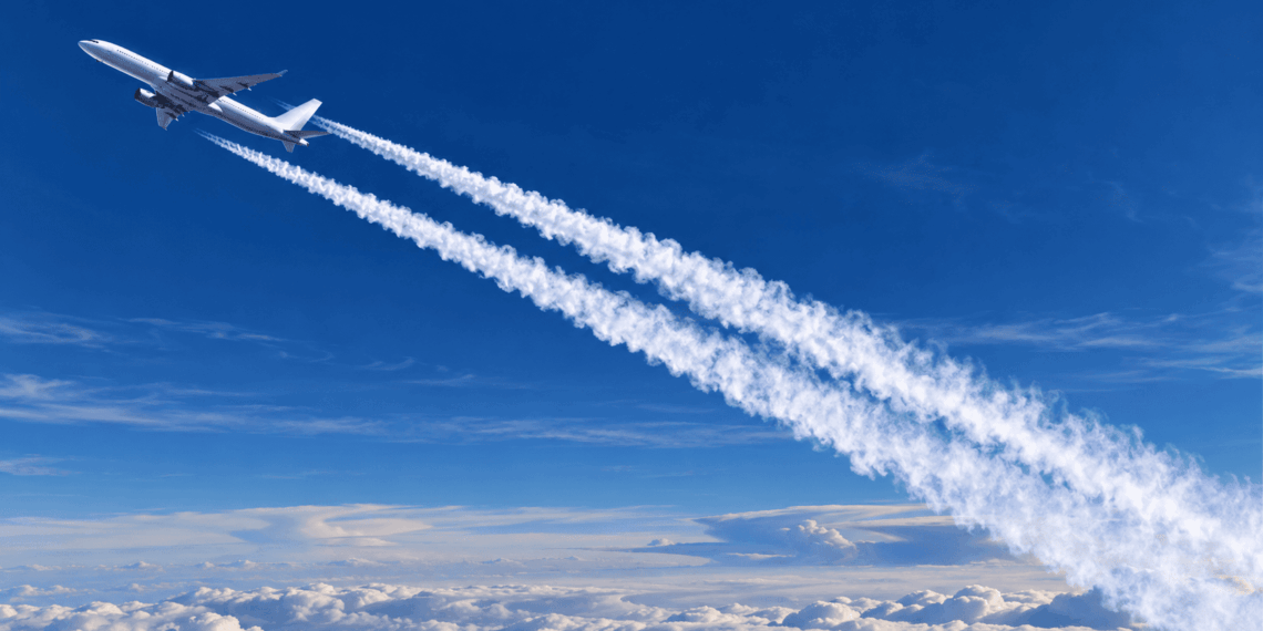Avião comercial voando acima das nuvens e deixando dois rastros brancos no céu azul.