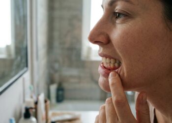 Pessoa observa a gengiva no espelho ao perceber sinais de inflamação.