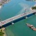 Ponte de Guaratuba cruza a baía enquanto uma balsa aparece ao fundo como referência à antiga travessia.
