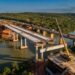 Vista aérea ilustrativa da nova ponte de concreto em construção sobre o Rio Jequitinhonha, ao lado da travessia antiga da BR-101, em Itapebi, Bahia.