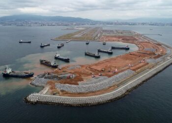 Corte ilustrativo do solo sob o aeroporto de Kansai mostrando o aterro, as camadas de argila marinha e o processo de recalque.