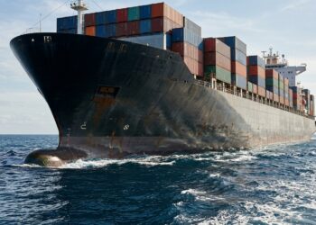 Navio cargueiro de aço transporta contêineres enquanto flutua no oceano.