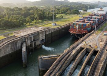 Navio de grande porte dentro de uma câmara de eclusa enquanto o nível da água é ajustado para permitir sua passagem pelo canal.