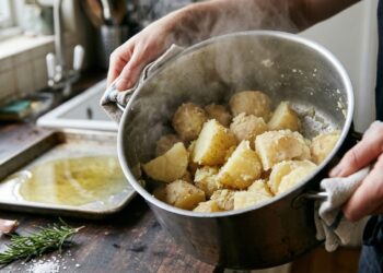 Batatas pré-cozidas são chacoalhadas na panela para criar uma superfície irregular antes de ir ao forno.
