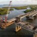 Representação aérea da desmontagem de uma ponte de concreto no Estreito dos Mosquitos, com guindaste e ponte paralela em operação na BR-135.