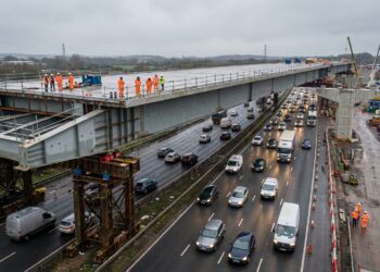 Viaduto de 4.600 toneladas avança sobre a M6 com carros passando por baixo.