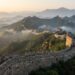 Grande Muralha da China atravessa montanhas íngremes com torres de vigia históricas.