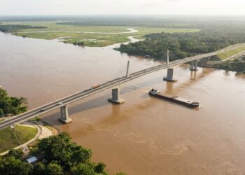 Ilustração conceitual de uma ponte rodoviária de 1.220 metros atravessando o Rio Mamoré entre Brasil e Bolívia, com vegetação amazônica nas margens.