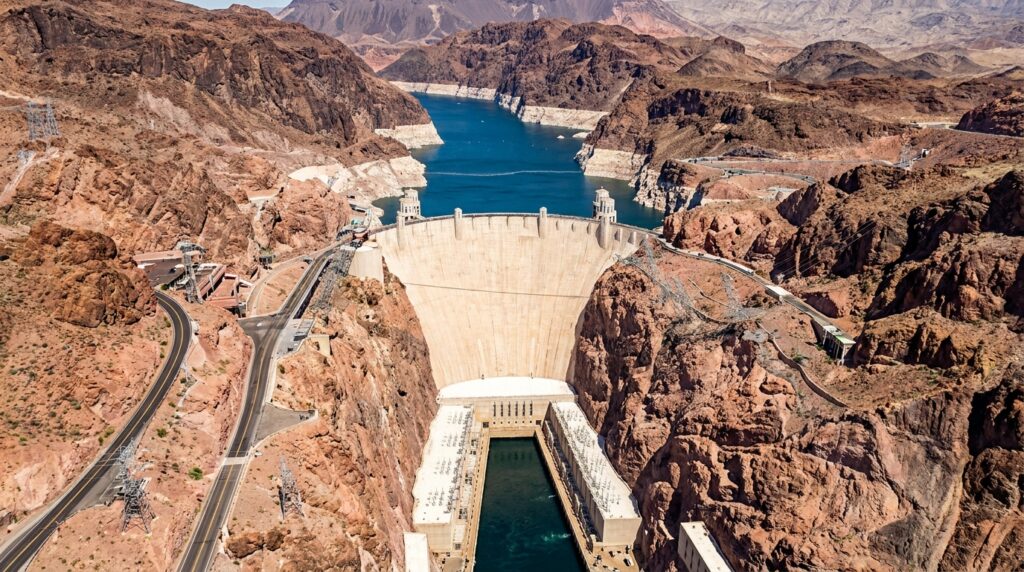 Vista aérea da Hoover Dam concluída, com o Lago Mead, o Rio Colorado e as montanhas áridas do sudoeste dos Estados Unidos.