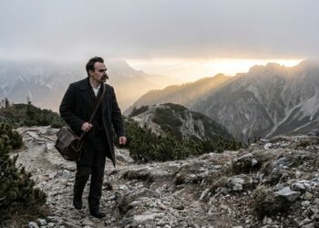 Friedrich Nietzsche caminha por uma trilha montanhosa difícil em direção ao horizonte.