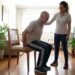 Pessoa com mais de 60 anos realiza exercício de sentar e levantar usando uma cadeira com supervisão profissional.