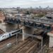 Nova ponte metálica elevada sobre linhas ferroviárias em Saltley, Birmingham, com trem elétrico passando sob a estrutura.