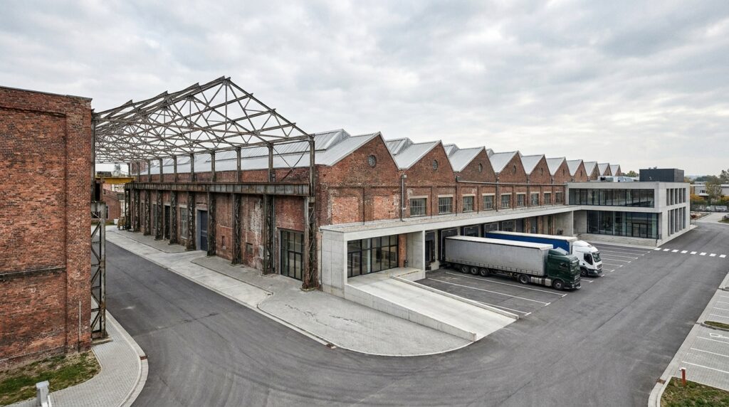 Antiga fábrica industrial adaptada para funcionar como centro de distribuição com docas para caminhões.