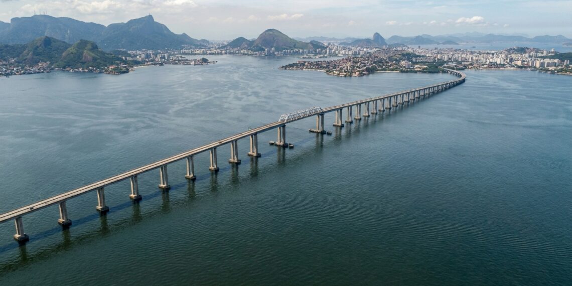 Vista aérea da Ponte Rio–Niterói atravessando a Baía de Guanabara, com seus longos trechos de concreto e o vão central metálico.