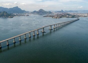 Vista aérea da Ponte Rio–Niterói atravessando a Baía de Guanabara, com seus longos trechos de concreto e o vão central metálico.