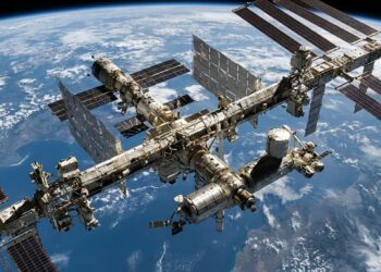 Estação Espacial Internacional com módulos habitáveis e grandes painéis solares sobre a curvatura azul da Terra.