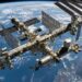 Estação Espacial Internacional com módulos habitáveis e grandes painéis solares sobre a curvatura azul da Terra.