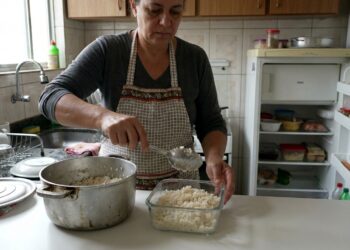 Pessoa colocando arroz cozido em um recipiente raso para armazenar as sobras com segurança.