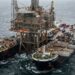 Navio Pioneering Spirit posicionado ao redor da estrutura superior de uma plataforma petrolífera em alto-mar.