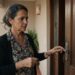 Mulher de aproximadamente 50 anos segura as chaves e olha com expressão de dúvida para a fechadura da porta de casa.