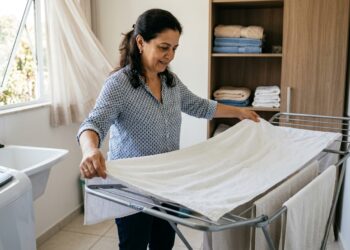 Mulher estende uma toalha totalmente aberta em local ventilado antes de guardar.