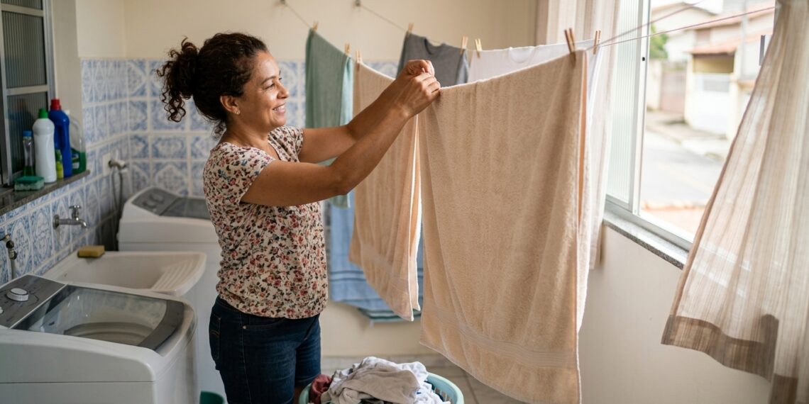 Mulher sacode uma toalha limpa e a estende totalmente aberta em local ventilado.
