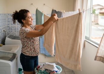 Mulher sacode uma toalha limpa e a estende totalmente aberta em local ventilado.