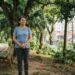 Mulher de 60 anos faz uma pausa durante a caminhada e observa as árvores em um parque urbano brasileiro.