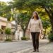 Mulher brasileira madura caminha sozinha por uma rua tranquila e arborizada, aproveitando um momento de liberdade e reflexão.