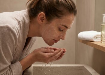 Mulher lavando o rosto antes de dormir para remover maquiagem, protetor solar e resíduos acumulados durante o dia.