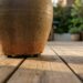 O deck de madeira da varanda começou a apodrecer exatamente embaixo dos vasos de plantas grandes? A umidade presa sem circulação destrói o piso